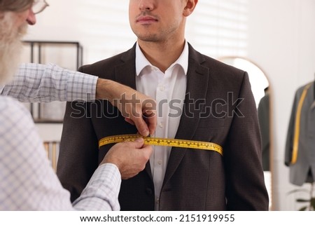 Professional tailor measuring client's chest circumference in atelier, closeup Royalty-Free Stock Photo #2151919955
