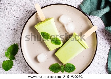Vegetarian popsicle made from matcha tea, coconut milk and mint on a plate on the table. Homemade gluten free dessert. Top view. Close-up