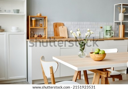 Background image of minimal kitchen interior in white with fresh flowers and fruits on dinner table, copy space
