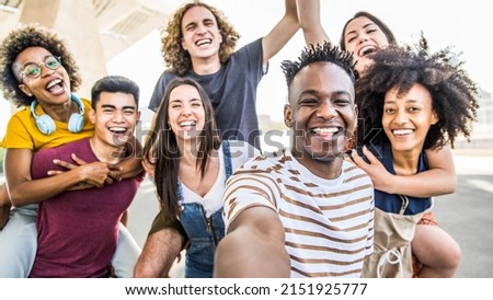 Group multiracial friends taking selfie picture with mobile smartphone outside - Happy young with hands up laughing at camera - Youth concept with guys and girls having fun walking on city street Royalty-Free Stock Photo #2151925777