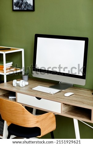 Vertical background image of white computer screen at home workplace against green wall, mock up