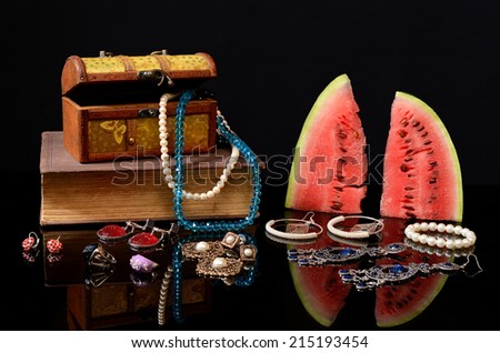 Box with jewelry, books and watermelon on the table
