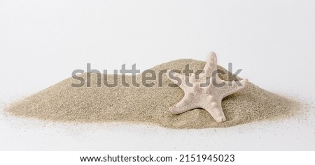 Holidays and sand beach. Close up of a starfish on the hipe of sand Royalty-Free Stock Photo #2151945023