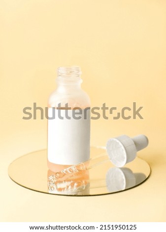 Cosmetic bottle with pipette lying next to it on the mirror