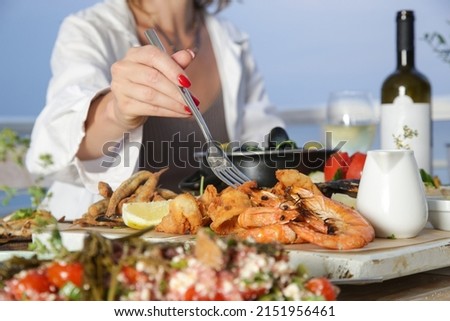 Young woman enjoying seafood platter during the sunset in the beach restaurant	 Royalty-Free Stock Photo #2151956461