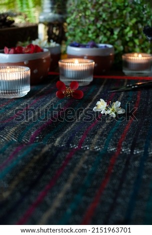 Spring flowers in ceramic cups and lighted candles on a woven rug. Alternative medicine, herbal medicine, aromatherapy or esoteric background with incense smoke.