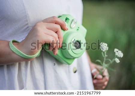 
photo of close-up instant camera print green in female hand on green background