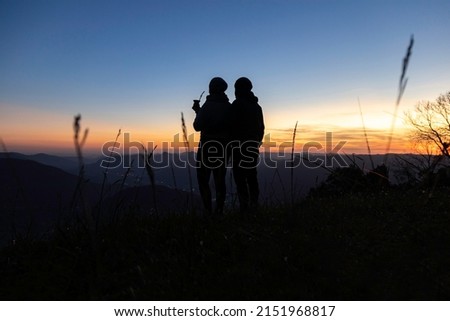 Silhouette of a couple with a yerba mate drink looking at the sunset on the top of a mountain, in Rio Grande do Sul highlands, Brazil Royalty-Free Stock Photo #2151968817