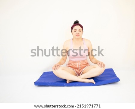 beautiful woman in yoga pose with closed eyes and hands on her legs, on blue mat