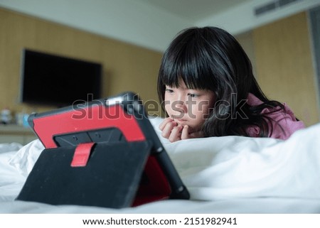 kid watching tablet on the bed, child addicted cartoon
