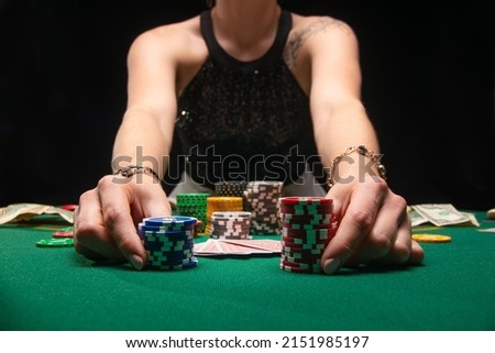 Girl plays poker in a casino, with chips, dollars, and wine. Concept of a gaming business.