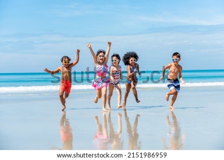 Group of Diversity little child boy and girl friends running and playing in sea water on tropical beach together on summer vacation. Happy children kid enjoy and fun outdoor lifestyle on beach holiday Royalty-Free Stock Photo #2151986959