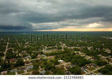 Dark stormy clouds forming on gloomy sky before heavy rainfall over suburban town area