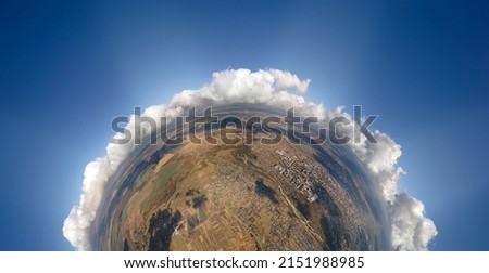 Aerial view from high altitude of little planet with distant city covered with puffy cumulus clouds forming before rainstorm. Airplane point of view of cloudy landscape