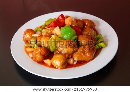Sweet and sour pork of traditional Cantonese yum-cha Asian gourmet cuisine meal food dish on the white serving plate and brown red table Royalty-Free Stock Photo #2151995953