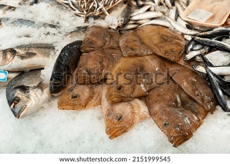 Fresh flounder fish on crushed ice in showcase of fish shop