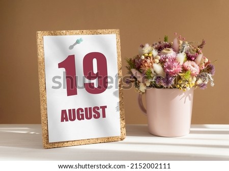 august 19. 19th day of month, calendar date.Bouquet of dead wood in pink mug on desktop.Cork board with calendar sheet on white-beige background. Concept of day of year, time planner, summer month.