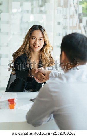 Pretty asian business woman shaking hands with businessman in her office during meeting Royalty-Free Stock Photo #2152003263