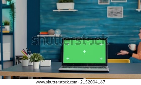 Green screen on modern laptop computer in living room, used by female student. Isolated background with blank chroma key and mockup copy space template on device with technology.