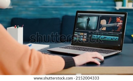 Multimedia designer using software to edit video footage on laptop at desk, learning to use production application online. Design student working on film montage to create media content. Royalty-Free Stock Photo #2152004333