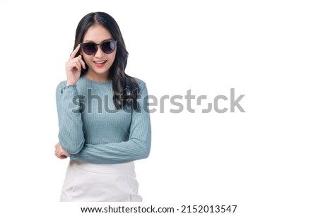 Portrait trendy asian woman wear sunglasses standing on white background. Gorgeous positive young lady holding hand on sunglasses laughing with copy space over isolated. Lifestyle summer concept.