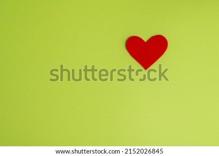 Red heart shaped cutout on green background. Concept of charity and healthcare donation. Love design element. Horizontal, top view, copy space. Valentine celebration