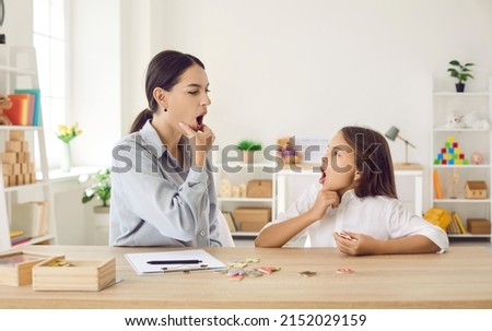 Happy child and young female speech therapist or mother doing mouth exercise, working on pronunciation problems, correcting sounds, fixing stuttering stammering impediment, and having fun together Royalty-Free Stock Photo #2152029159