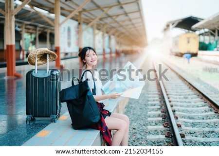 summer, relax, vacation, travel, portrait of a cute Asian girl looking at a map to plan a trip while waiting at the train station