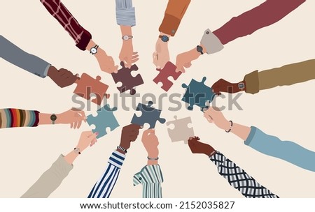 Group of multicultural business people with arms and hands in a circle holding a piece of jigsaw. Co-workers of diverse ethnic groups and cultures. Cooperate - collaborate. Teamwork Royalty-Free Stock Photo #2152035827
