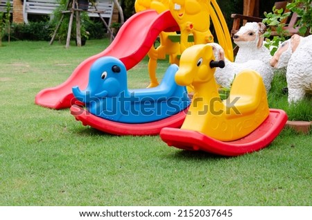 Colorful plastic rocking horse in playground. Lay on green grass background.