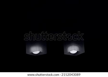 two lamps lighting dimly in the middle of the darkness. dim white light in a black and white abstract image