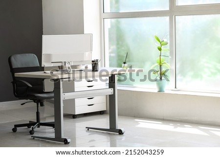 Standing desk with modern computer and chair in office Royalty-Free Stock Photo #2152043259