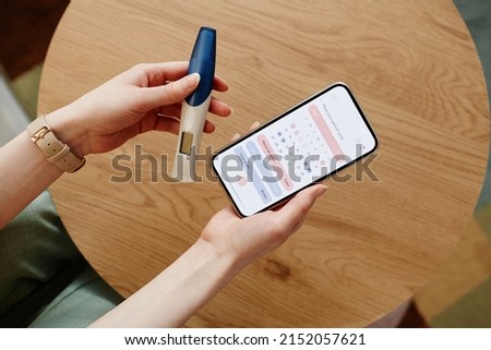 Close up of young woman calculating menstrual cycle using mobile app and holding pregnancy test Royalty-Free Stock Photo #2152057621