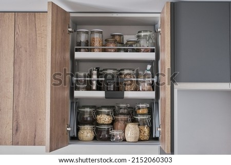 Variety of dry foods, grains, nuts, cereals in glass jars in kitchen cupboard. Zero waste storage concept. Royalty-Free Stock Photo #2152060303