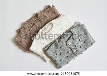 Stack of knitted clothes. Baby clothes. Needlework, hobby, knitting, handwork. Royalty-Free Stock Photo #2152061575