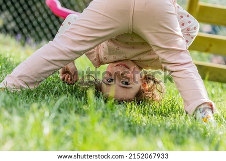 Cute little girl playing on a playground wearing rose trousers  Royalty-Free Stock Photo #2152067933