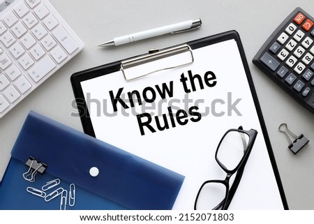 Know the Rules white paper with space for text in a folder with a clip, near a blue folder and a calculator on a gray background