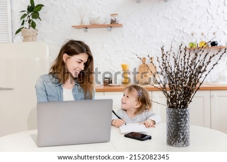 Beautiful single mother sitting at the desk with cute toddler, distantly working from home. Young business woman in maternity leave using laptop, searching in the internet ideas for new project. Royalty-Free Stock Photo #2152082345
