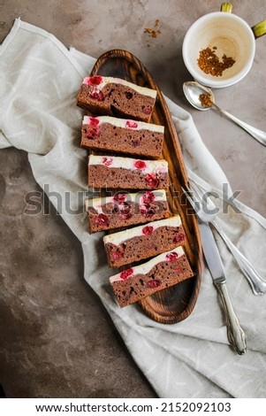 Chocolate brownie with cherries and cheese layer. Many pieces of chocolate dessert with berries on a wooden board
