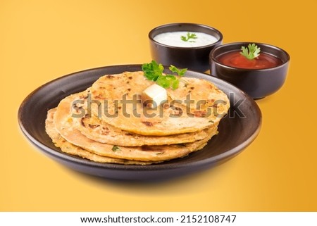 Potato Stuffed Flat Bread or Aloo paratha is a Traditional Indian food. served with curd, butter or ghee. selective focus. isolated on yellow background. Royalty-Free Stock Photo #2152108747