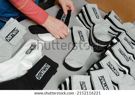 Hosiery factory. Mass production of clothing. Stacking and laying socks. Socks in different colors and sizes. Tights, leggings, stockings, stockings. Underwear. Textile products. Hand layout.  Royalty-Free Stock Photo #2152116221