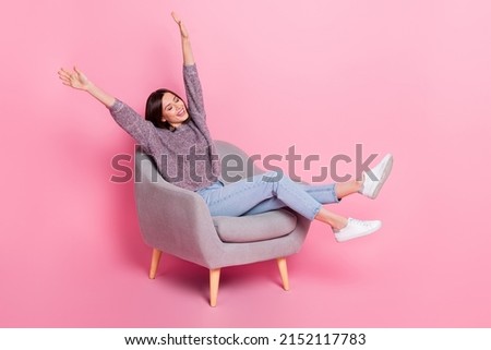 Photo of adorable shiny lady dressed sweater sitting chair riding arms isolated pink color background