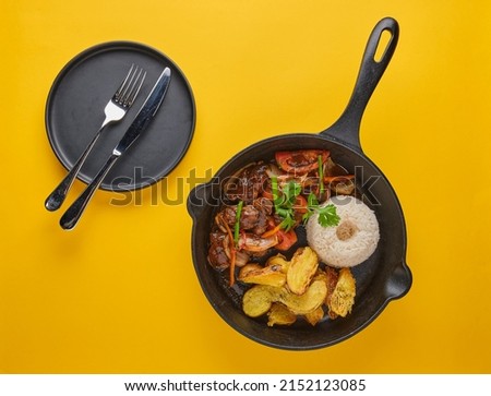 Peruvian d food - Lomo saltado - beef tenderloin with purple onion, yellow pepper, tomatoes served in a black pan with french fries and rice. Top view Royalty-Free Stock Photo #2152123085