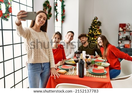 Group of young people having christmas dinner make selfie by the smartphone at home.