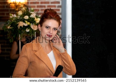 TV presenter, wedding karaoke host. Young woman in an orange with a microphone