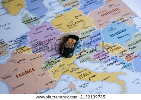 Toy car on Europe map, side view, world trip concept, miniature green sport car going to Italy, country and Europe tour