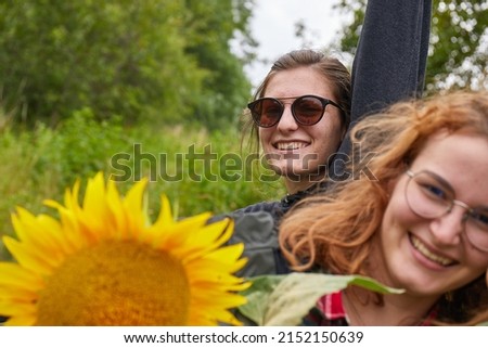 Girls posing for picture with sunflower smiling having fun, rainy overcast weather