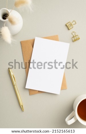 Business concept. Top view vertical photo of paper sheet craft paper envelope gold pen binder clips cup of tea and vase with white lagurus flowers on pastel grey background with copyspace