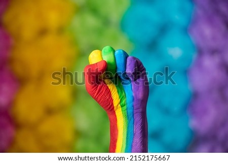 Rainbow colors painted hand raised making fist, sign. Rainbow colors background. LGBT pride symbol.  Royalty-Free Stock Photo #2152175667