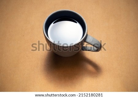 A cup of hot coffee on a cardboard box in low key picture style, lens vignetting added